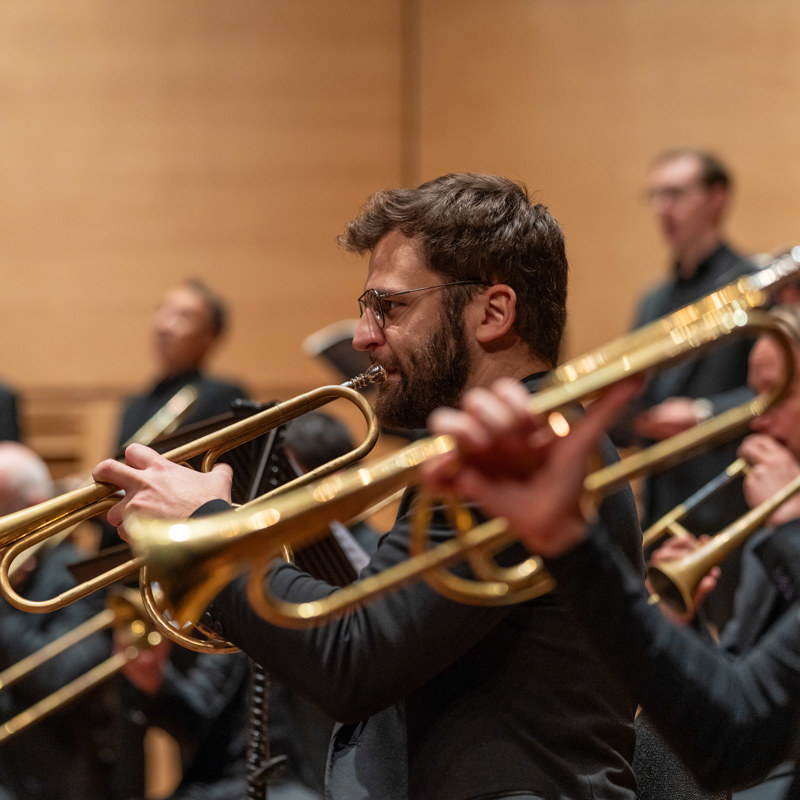 Orkest speelt muziek met op de voorgrond mensen die trompet spelen